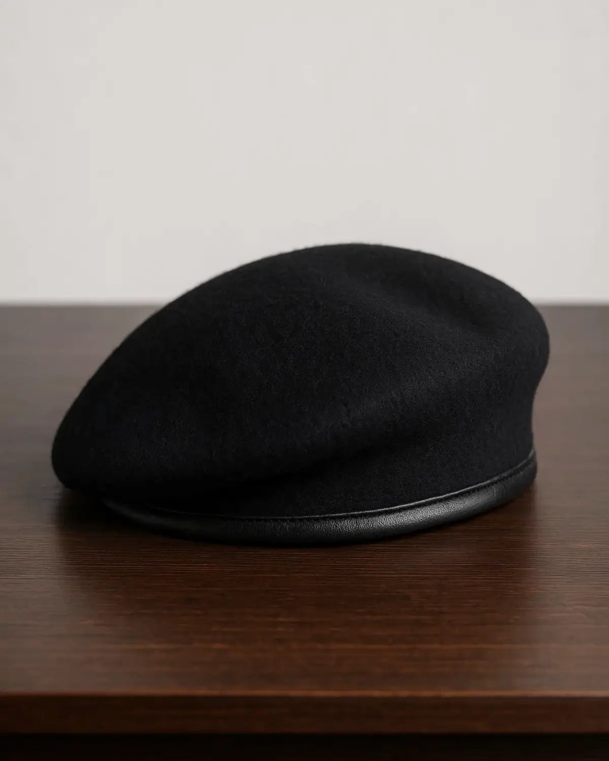 Boina Masculina Francesa de Lã na cor preta ajustável sobre mesa de madeira escura, estilo sofisticado e minimalista.

