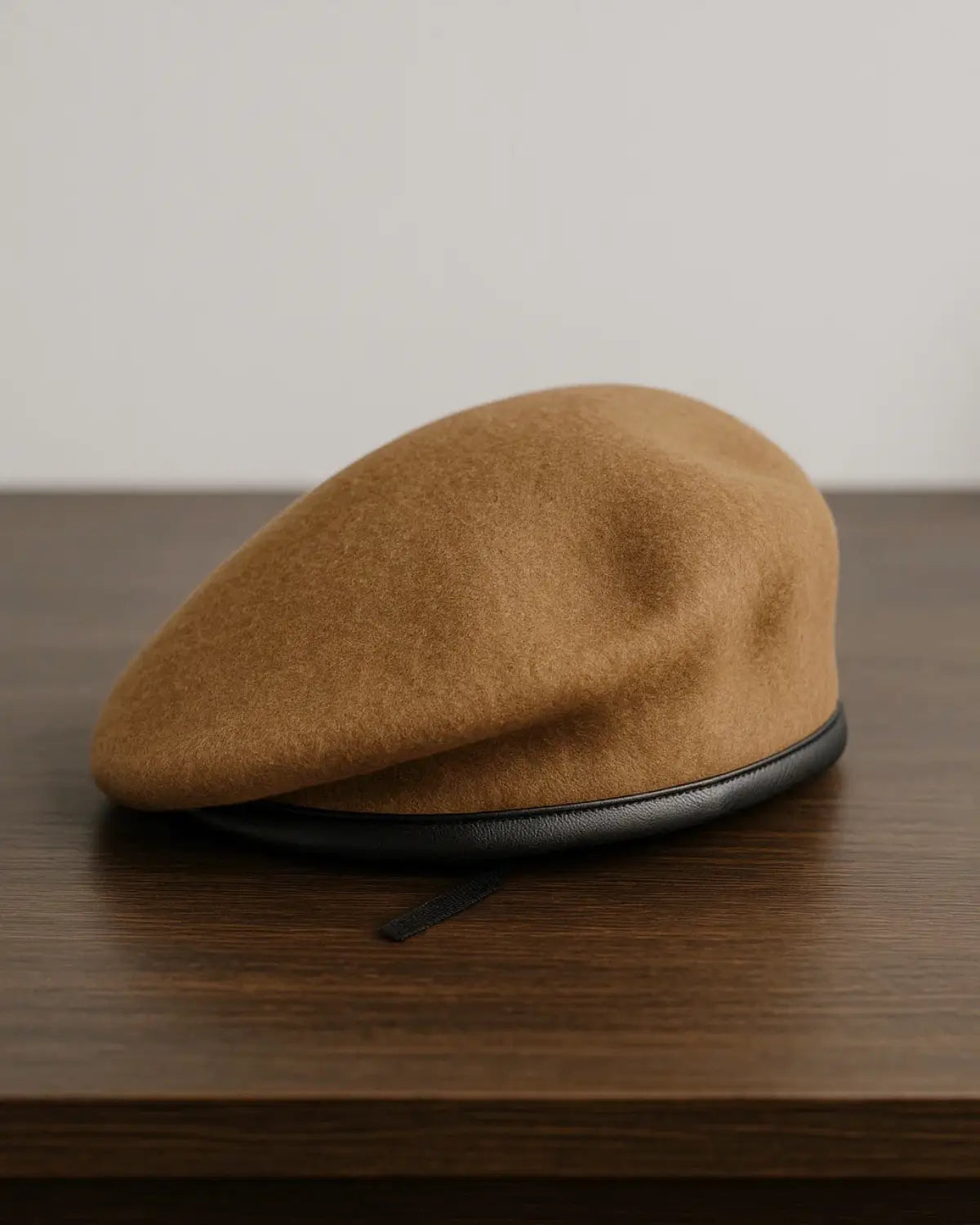 Boina Masculina Francesa Lã Ajustável Brown posicionada sobre mesa de madeira escura, destaque para o design arredondado e sofisticado.