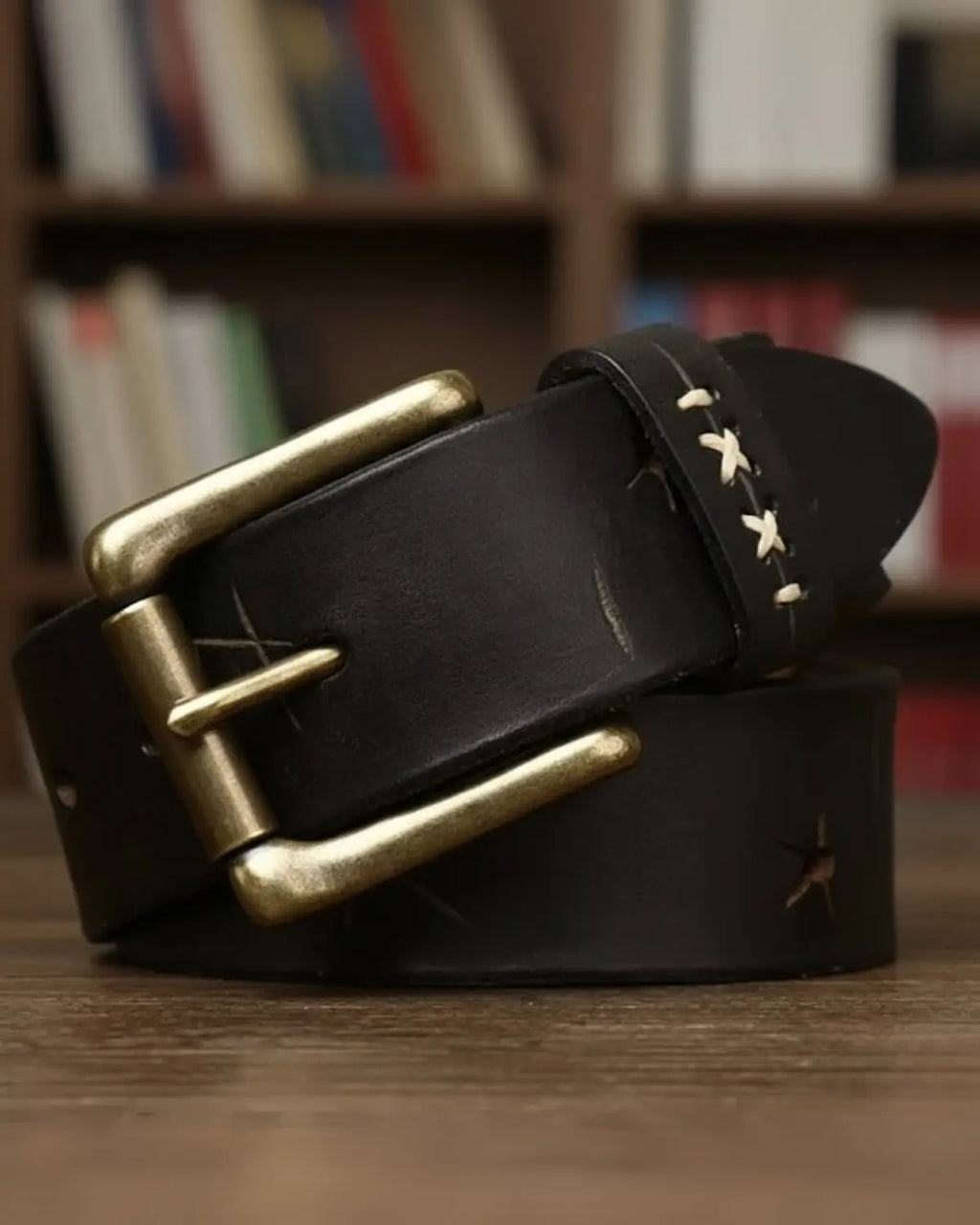 Cinto masculino couro legítimo preto Mercer Black enrolado mesa madeira, fivela latão envelhecido, detalhe costura artesanal clara