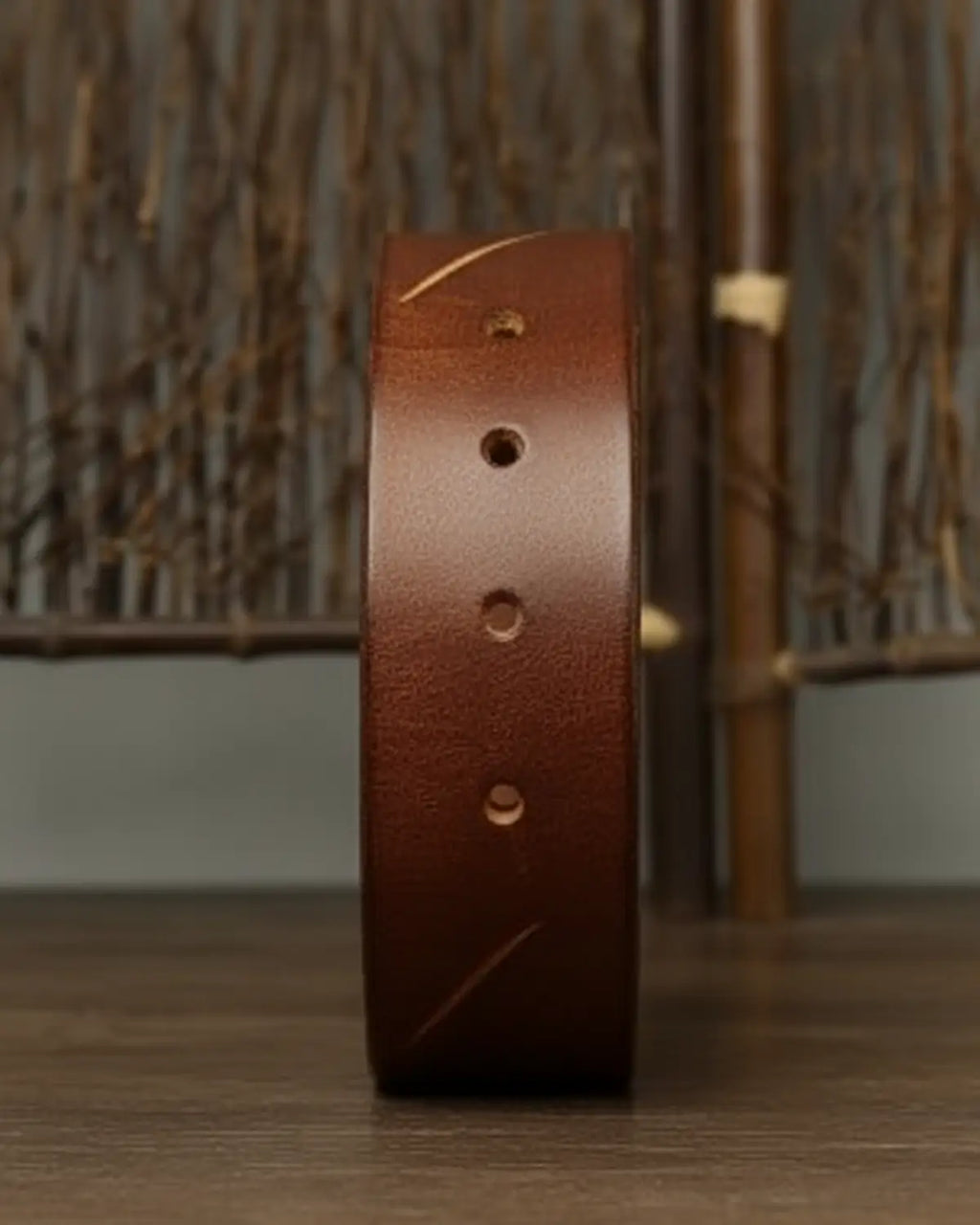 Detalhe lateral do cinto masculino Mercer Khaki, couro legítimo, perfurações artesanais, fundo neutro, estilo clássico