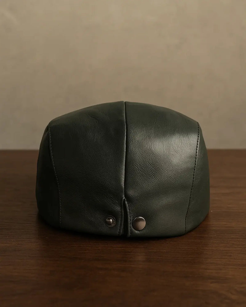 Vista traseira da boina masculina inglesa de couro preta sobre mesa de madeira escura