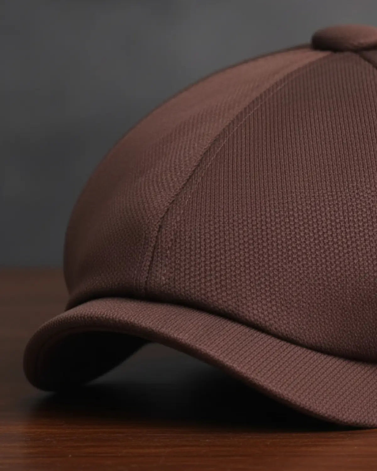 Close da boina italiana masculina marrom em poliéster, destacando textura, costura e acabamento premium sobre mesa de madeira