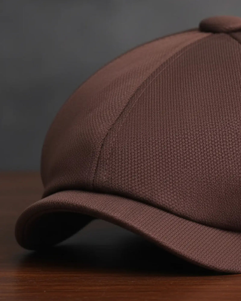 Close da boina italiana masculina marrom em poliéster, destacando textura, costura e acabamento premium sobre mesa de madeira