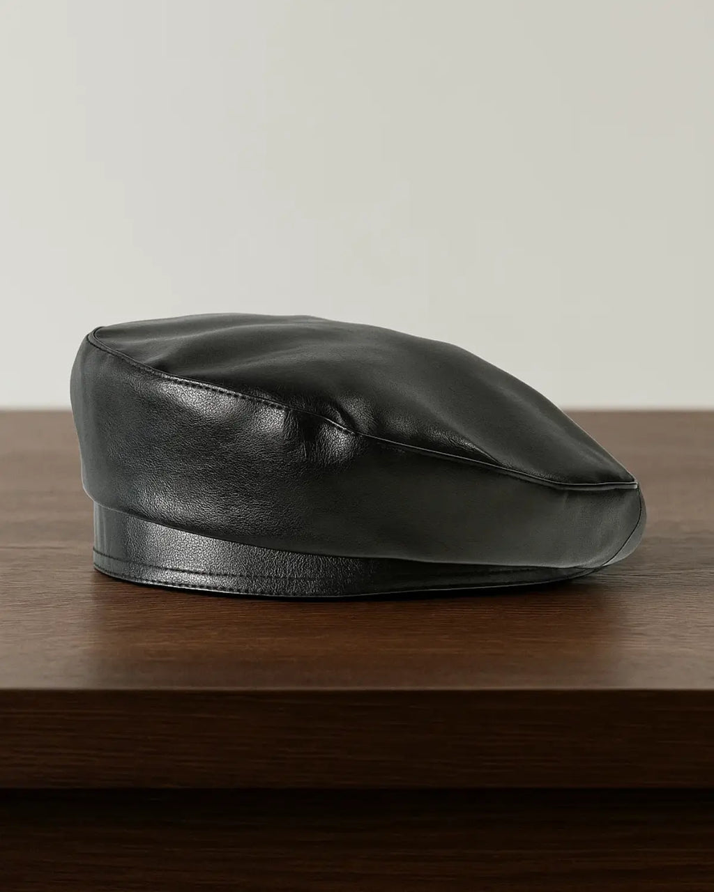 Boina masculina francesa em couro preto sobre mesa de madeira, estilo clássico e sofisticado