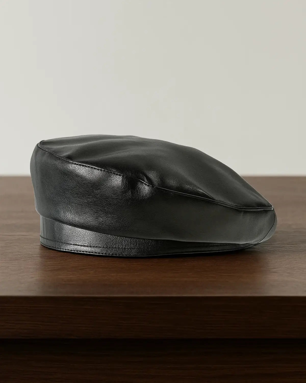 Boina masculina francesa em couro preto sobre mesa de madeira, estilo clássico e sofisticado