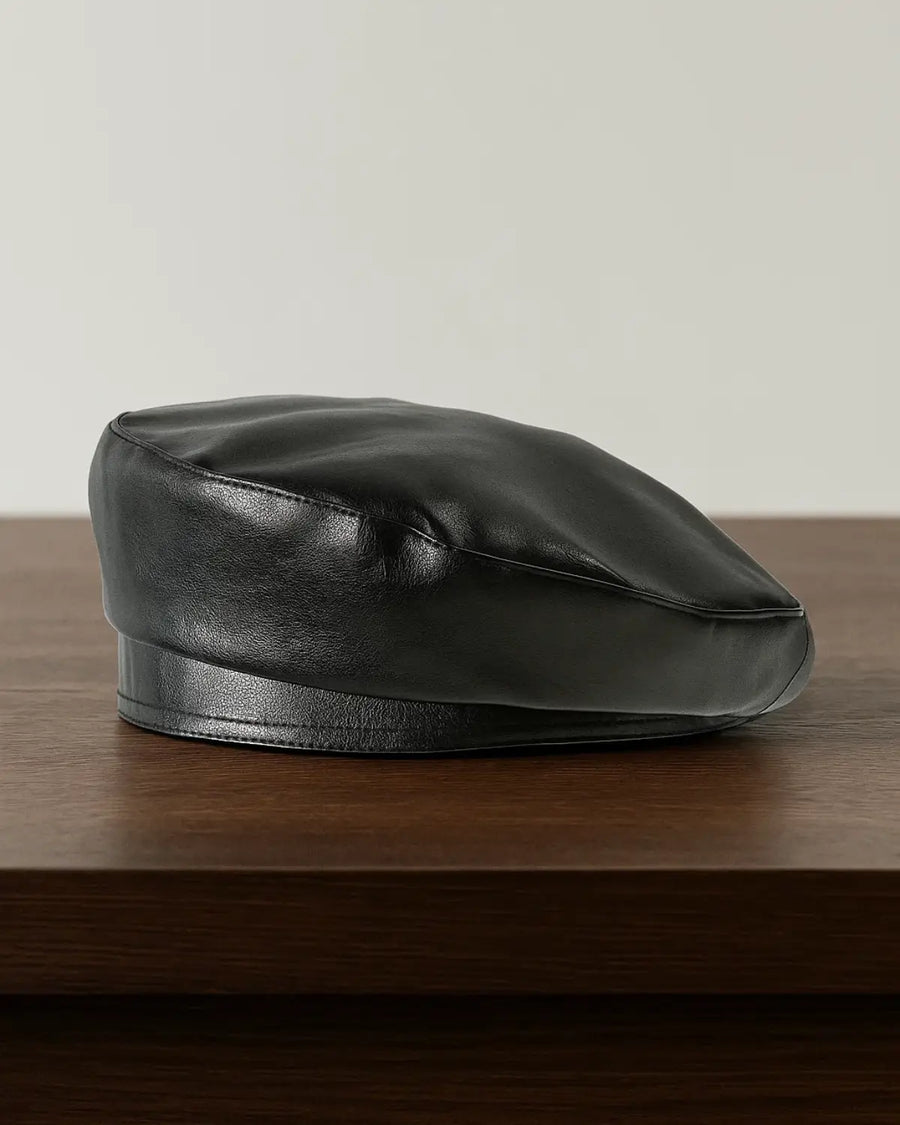 Boina masculina francesa em couro preto sobre mesa de madeira, estilo clássico e sofisticado