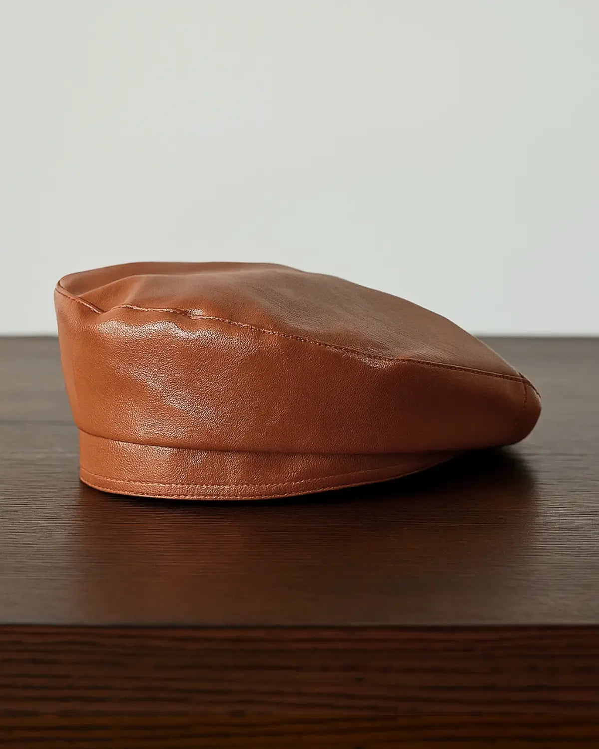 Boina masculina francesa em couro marrom sobre mesa de madeira, estilo sofisticado e clássico
