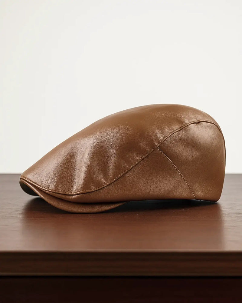 Boina masculina inglesa de couro marrom sobre mesa de madeira escura com fundo neutro