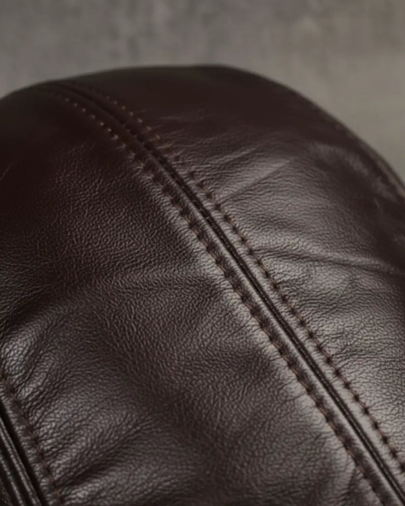 Detalhe em close da boina masculina inglesa de couro legítimo coffee Dorian, destacando textura do couro premium e costura reforçada sofisticada