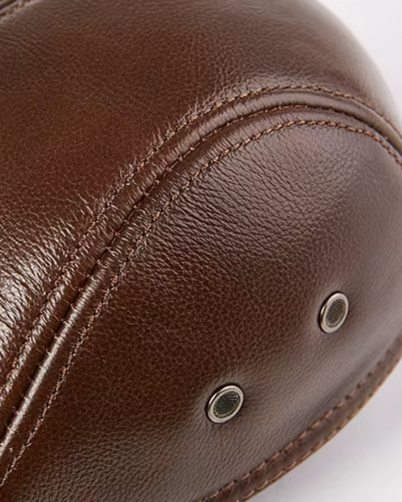 Detalhe close da textura do couro legítimo marrom na boina masculina inglesa Dorian Brown, mostrando costuras duplas reforçadas e acabamento premium