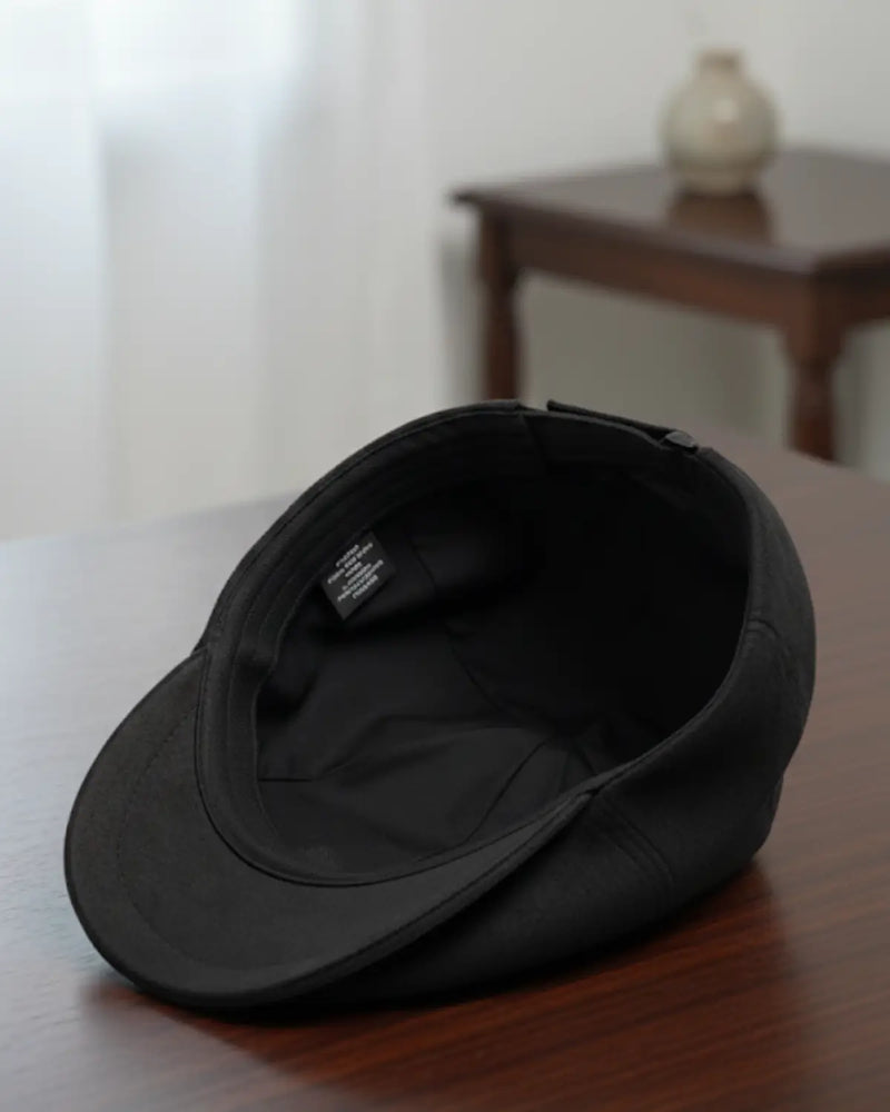 Forro interno e acabamento da boina masculina inglesa em couro vegano preto, sobre mesa de madeira, qualidade e sofisticação Cappel