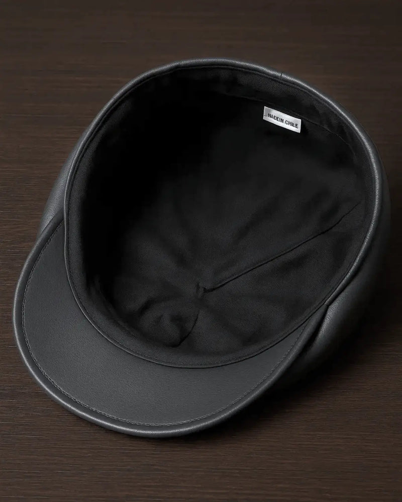 Vista interna da boina italiana de couro cinza com forro preto sobre superfície de madeira escura