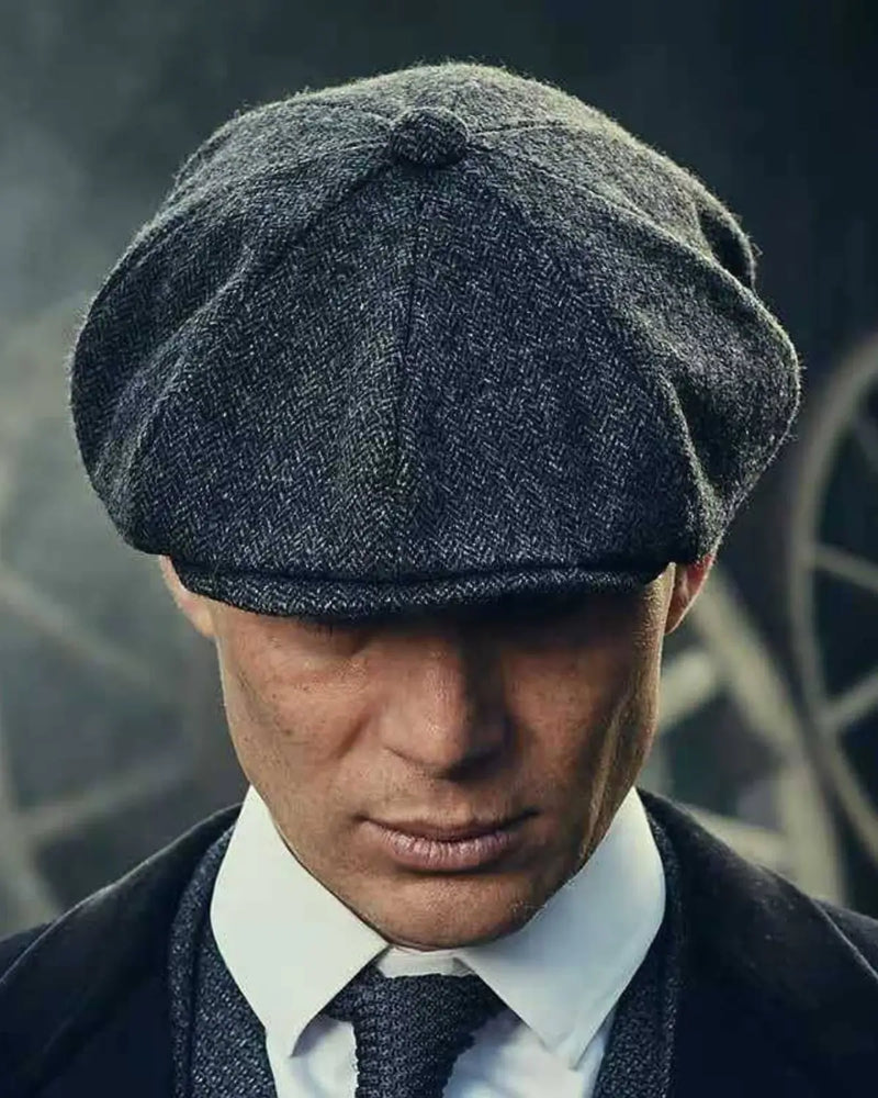 Detalhe do caimento da Boina Peaky Blinders no rosto de Thomas Shelby, destacando a aba curva e estruturada que cria uma sombra misteriosa sobre os olhos.
