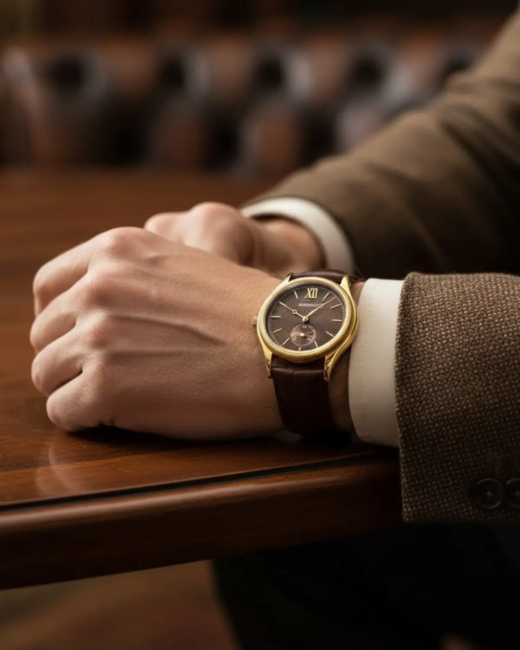 Relógio monarch Brown repousando sobre mesa de madeira — design clássico com acabamento em ouro polido