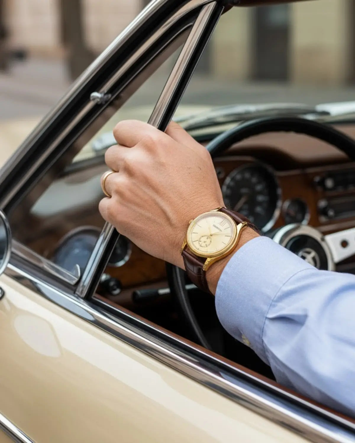 Detalhe do Relógio Masculino monarch Gold no pulso de homem dirigindo carro vintage — luxo sutil e design tradicional