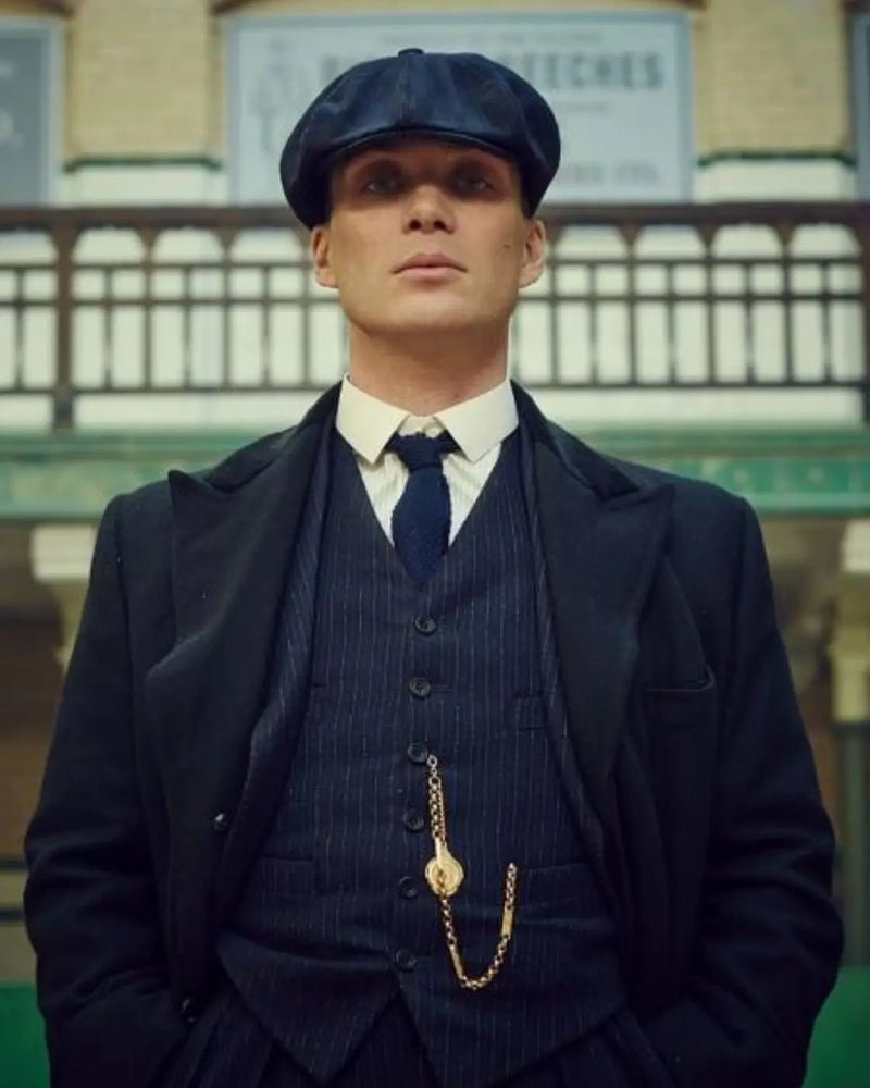 Thomas Shelby (Cillian Murphy) usando a clássica Boina Peaky Blinders estilo Newsboy combinada com terno e gravata azul, inspirando liderança e elegância.