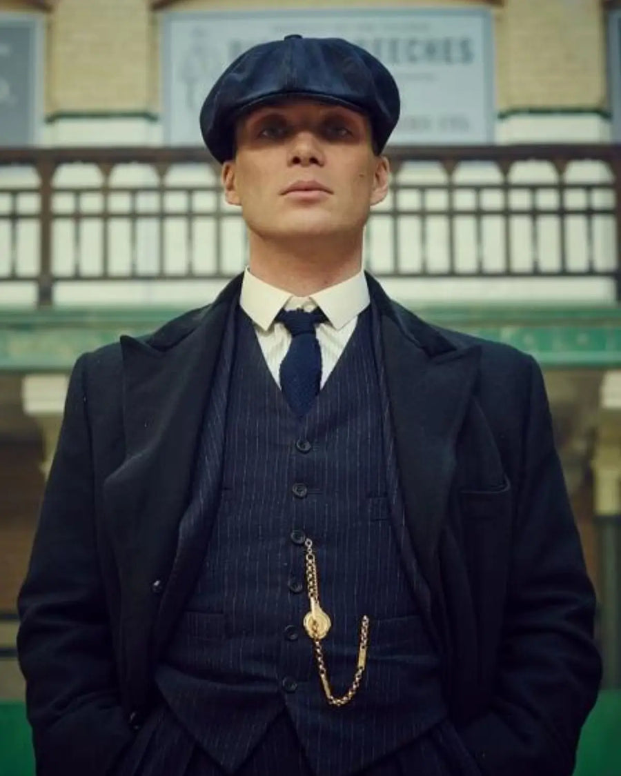 Thomas Shelby (Cillian Murphy) usando a clássica Boina Peaky Blinders estilo Newsboy combinada com terno e gravata azul, inspirando liderança e elegância.